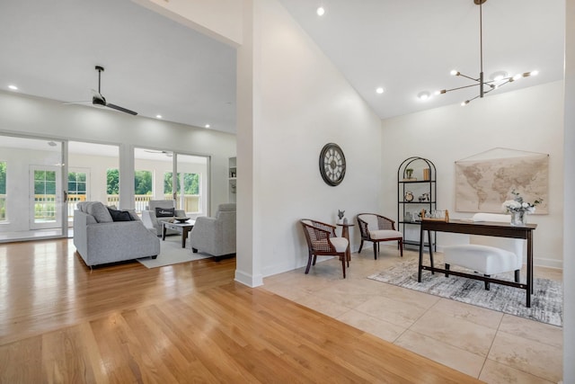 interior space with light wood-type flooring, ceiling fan with notable chandelier, and high vaulted ceiling