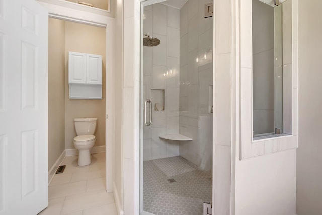 bathroom featuring tile patterned flooring, toilet, and an enclosed shower