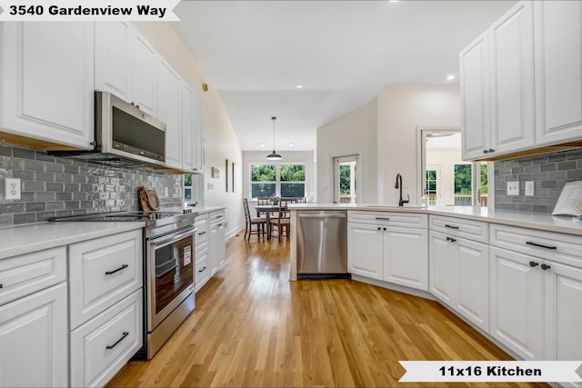 kitchen featuring white cabinets, decorative light fixtures, and appliances with stainless steel finishes