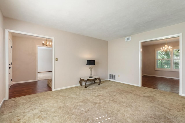 spare room featuring an inviting chandelier, carpet floors, and visible vents