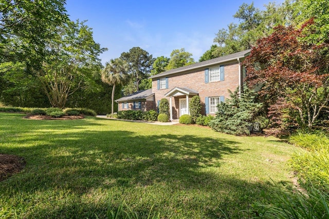 colonial-style house featuring brick siding and a front yard