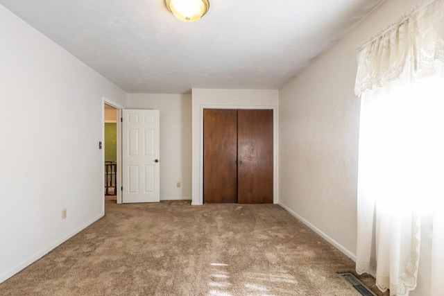 unfurnished bedroom with baseboards, carpet, a closet, and visible vents