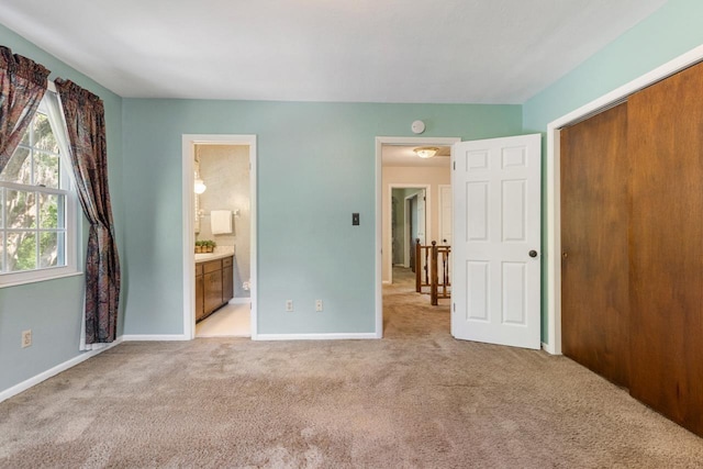 unfurnished bedroom with baseboards, light carpet, a closet, and connected bathroom