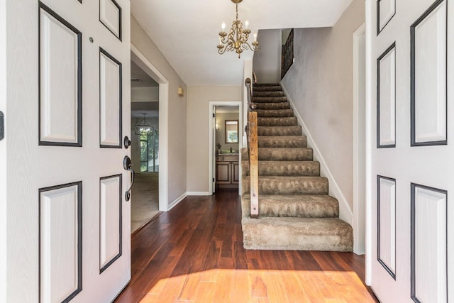 entrance foyer with baseboards, dark wood finished floors, a chandelier, and stairway