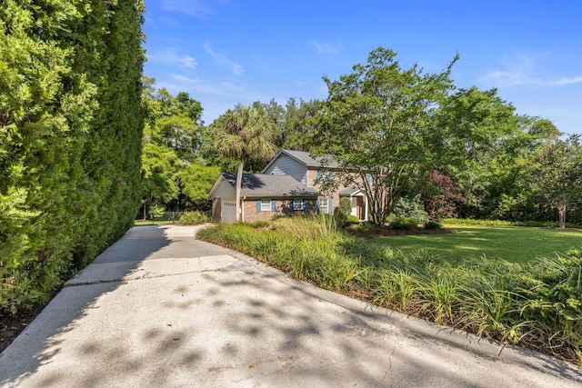 view of property exterior with brick siding, an attached garage, and driveway