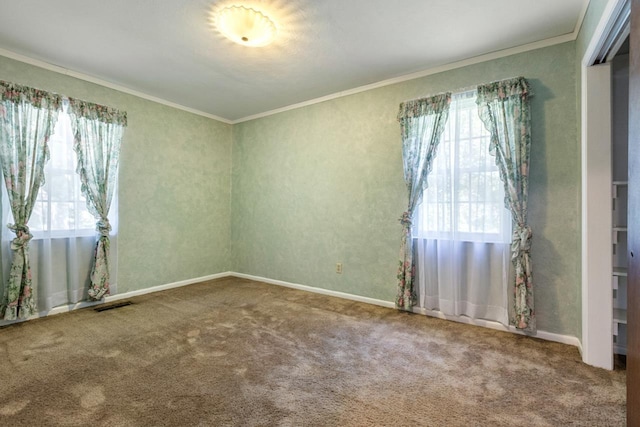 carpeted spare room with crown molding, baseboards, and visible vents