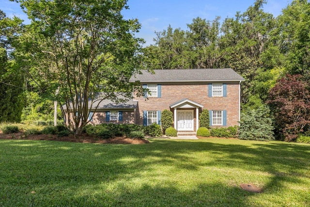colonial-style house featuring brick siding and a front yard