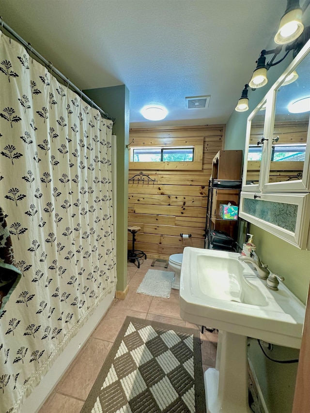 full bathroom featuring a shower with curtain, wood walls, visible vents, toilet, and tile patterned flooring