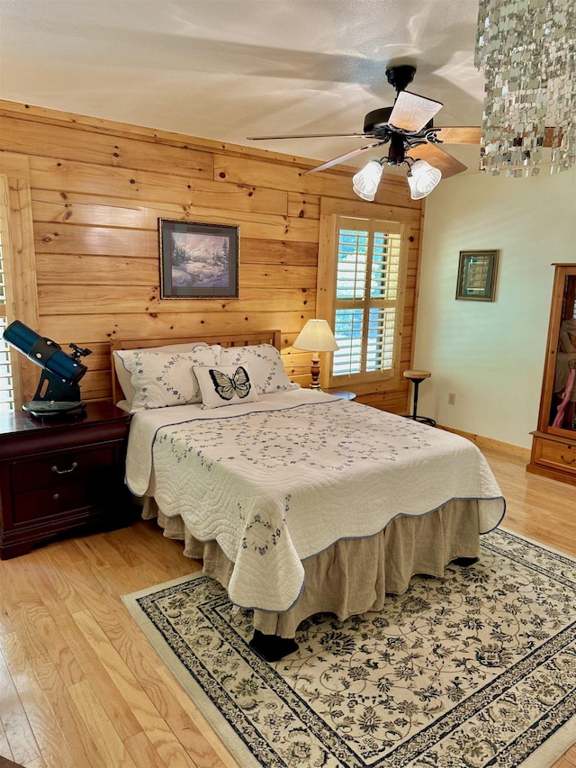 bedroom featuring wood walls, a ceiling fan, and light wood finished floors