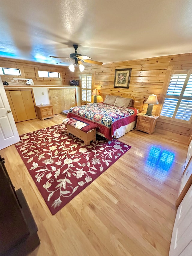 bedroom with wood walls and light wood finished floors