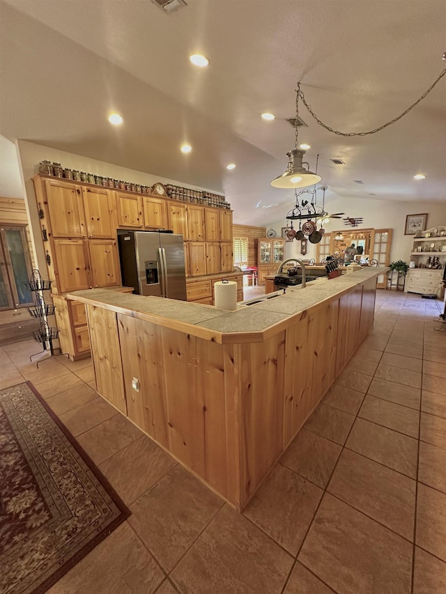 kitchen with recessed lighting, light brown cabinets, stainless steel fridge, light tile patterned flooring, and vaulted ceiling