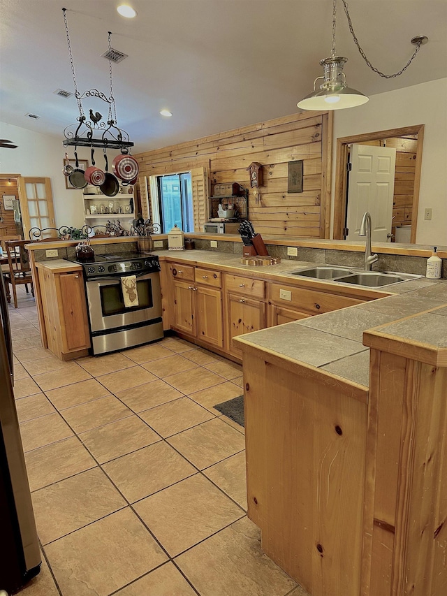 kitchen featuring light tile patterned floors, a sink, visible vents, pendant lighting, and stainless steel range with electric stovetop