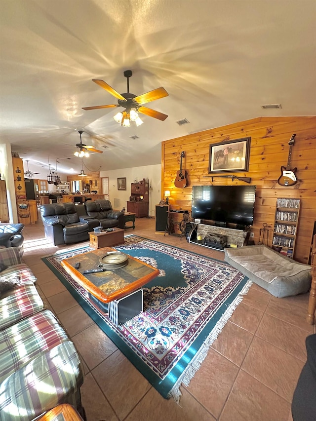 living room with wooden walls, visible vents, ceiling fan, and tile patterned flooring