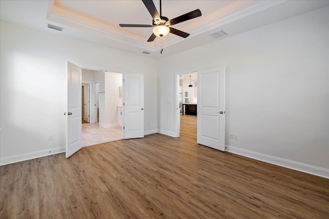 unfurnished bedroom with ornamental molding, hardwood / wood-style flooring, ceiling fan, and a raised ceiling