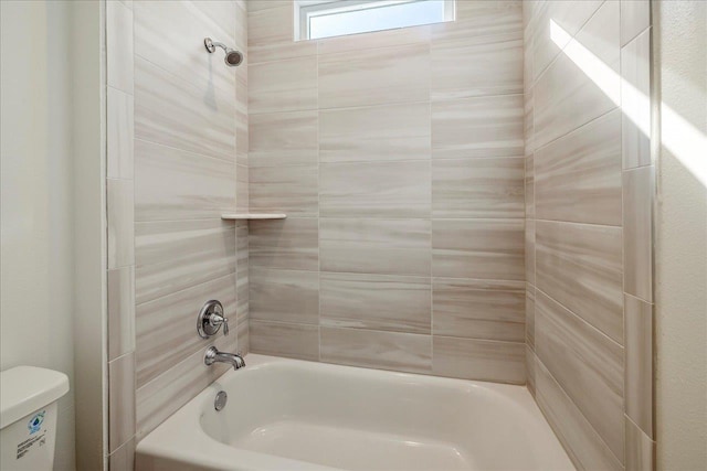 bathroom with tiled shower / bath combo and toilet