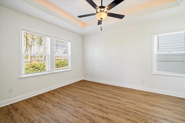 unfurnished room featuring a tray ceiling, ceiling fan, crown molding, and wood-type flooring