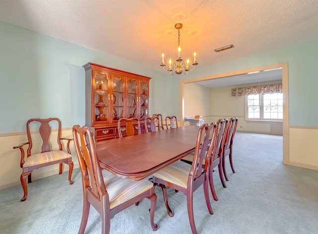 dining room featuring a textured ceiling, light colored carpet, and an inviting chandelier