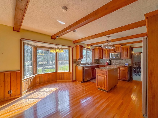 kitchen with a center island, stainless steel appliances, light hardwood / wood-style floors, a textured ceiling, and decorative light fixtures