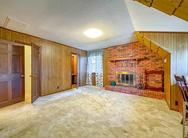 unfurnished living room featuring a textured ceiling, wood walls, light colored carpet, and a fireplace