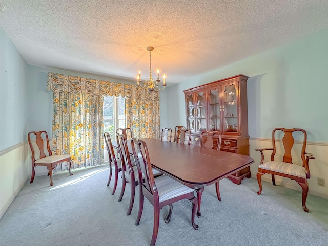 carpeted dining area with a textured ceiling and a chandelier