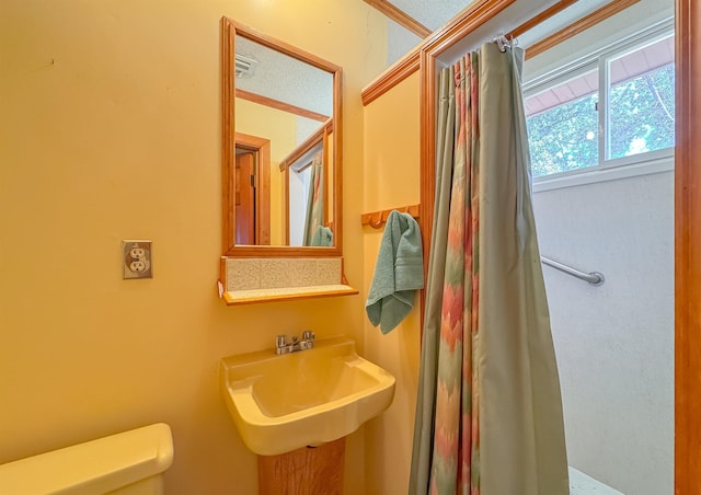 bathroom with a textured ceiling, toilet, and sink