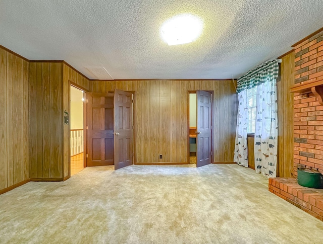 unfurnished bedroom featuring light carpet, wooden walls, and a textured ceiling