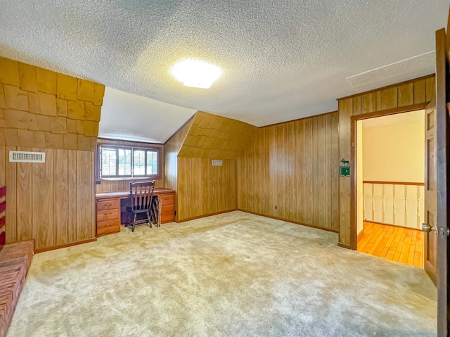 bonus room featuring wooden walls, light colored carpet, and vaulted ceiling