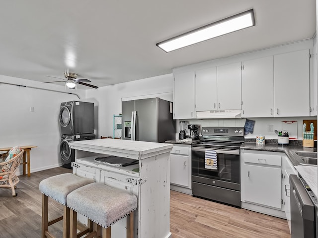 kitchen featuring stacked washer and dryer, light wood-type flooring, stainless steel appliances, and white cabinetry