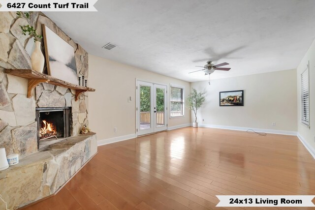 6427 Count Turf Trl, Tallahassee, FL 32309 - unfurnished living room with a fireplace, a ceiling fan, light wood-style flooring, baseboards, and french doors