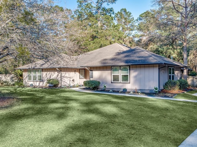 ranch-style house with a shingled roof, fence, and a front yard