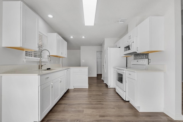 kitchen featuring white appliances, a textured ceiling, hardwood / wood-style floors, white cabinetry, and sink