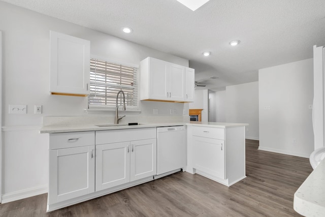 kitchen featuring kitchen peninsula, white dishwasher, a textured ceiling, white cabinets, and sink