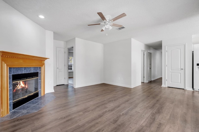 unfurnished living room with dark hardwood / wood-style flooring, a fireplace, ceiling fan, and a textured ceiling