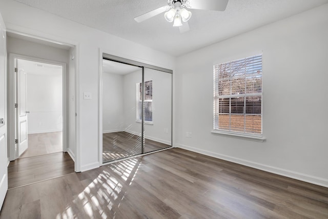 unfurnished bedroom with ceiling fan, a closet, a textured ceiling, and hardwood / wood-style flooring