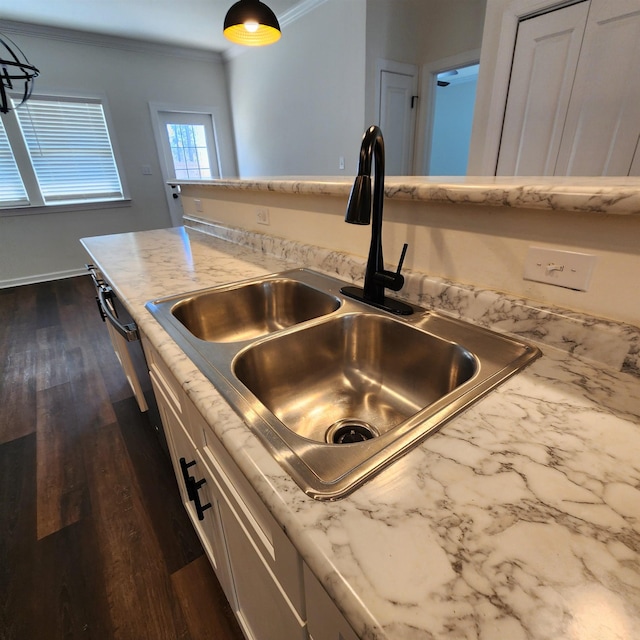 kitchen featuring sink, dark wood-type flooring, light stone counters, pendant lighting, and ornamental molding