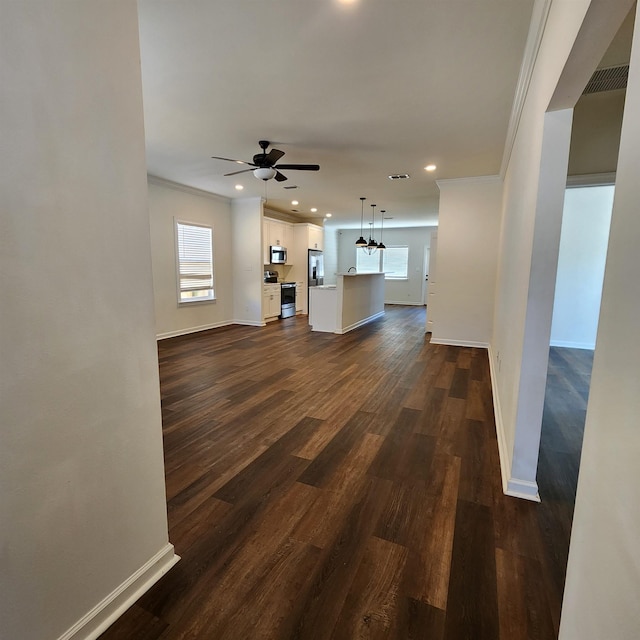 unfurnished living room featuring a healthy amount of sunlight, ornamental molding, and dark wood-type flooring