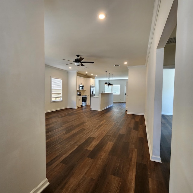 unfurnished living room featuring ceiling fan, crown molding, and dark wood-type flooring