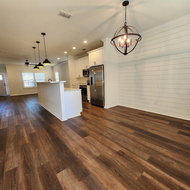 kitchen with white cabinets, wood walls, stainless steel appliances, and hanging light fixtures