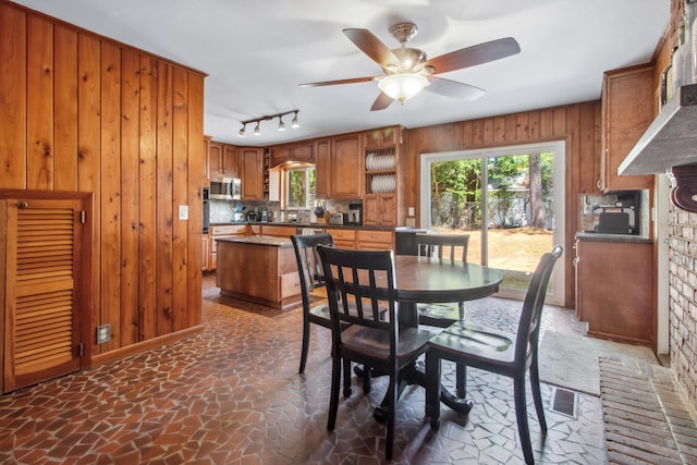 dining area featuring plenty of natural light, wooden walls, visible vents, and ceiling fan