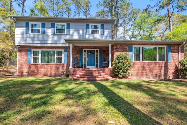 view of front of house with covered porch, brick siding, a front yard, and crawl space