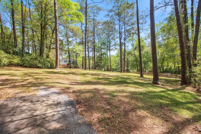 view of yard featuring a wooded view and fence