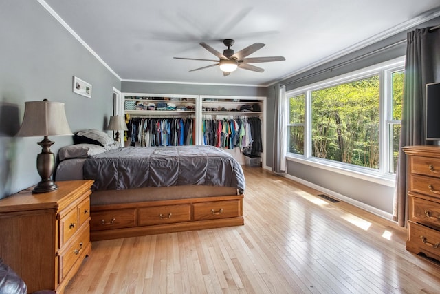 bedroom with crown molding, baseboards, light wood finished floors, and visible vents