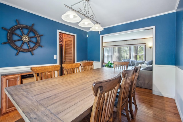 dining area featuring wood finished floors and crown molding
