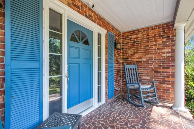 property entrance featuring brick siding and a porch