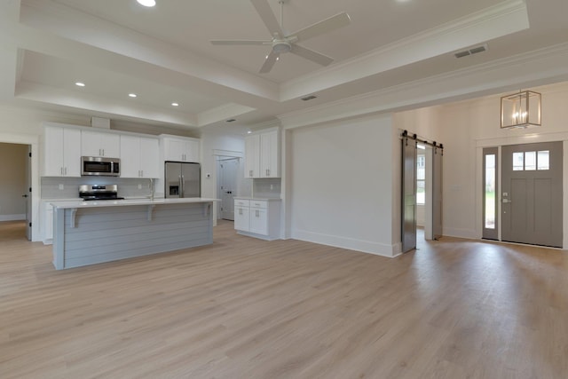 kitchen featuring decorative light fixtures, white cabinets, appliances with stainless steel finishes, and a barn door