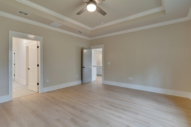 unfurnished room featuring ceiling fan, a tray ceiling, crown molding, and light wood-type flooring