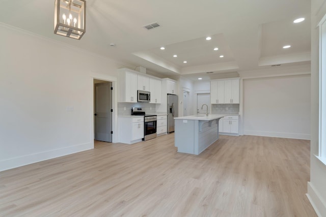 kitchen featuring appliances with stainless steel finishes, white cabinetry, an island with sink, decorative backsplash, and sink