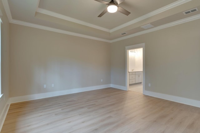 spare room with ceiling fan, light wood-type flooring, a tray ceiling, and ornamental molding