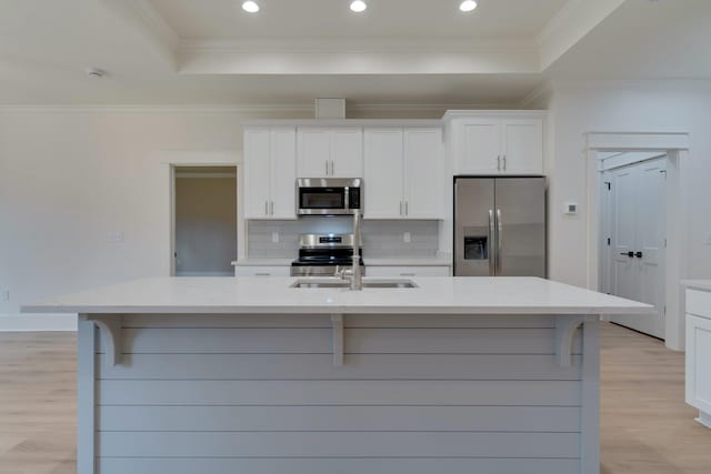 kitchen with light stone countertops, appliances with stainless steel finishes, a spacious island, white cabinets, and a tray ceiling