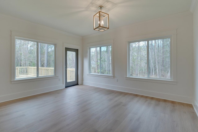 spare room featuring plenty of natural light, crown molding, and a notable chandelier